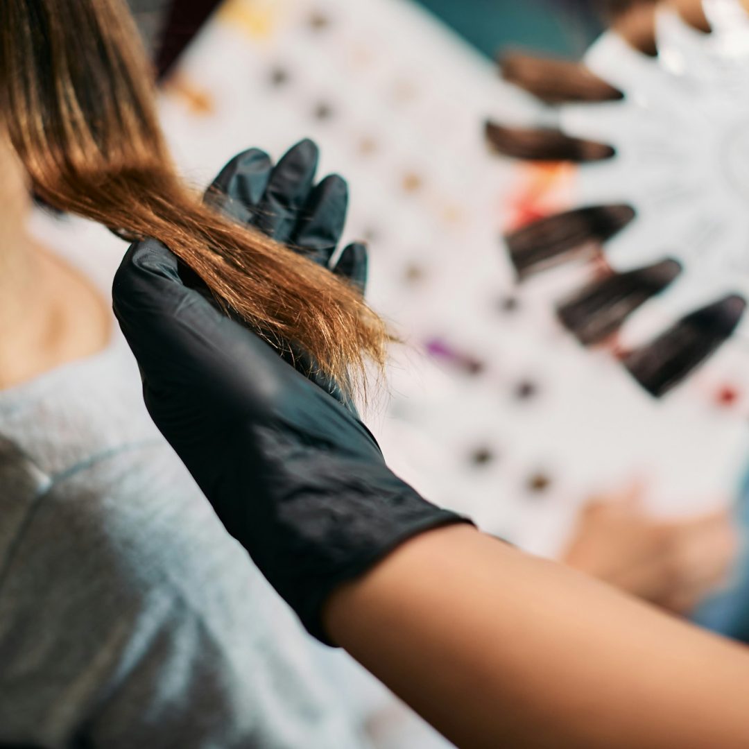 Close-up of hairdresser choosing hair color during treatment at the salon.